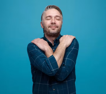 Middle age man with grey hair dark color shirt looking pleased happy hugging himself standing blue background 141793 133411 360x320